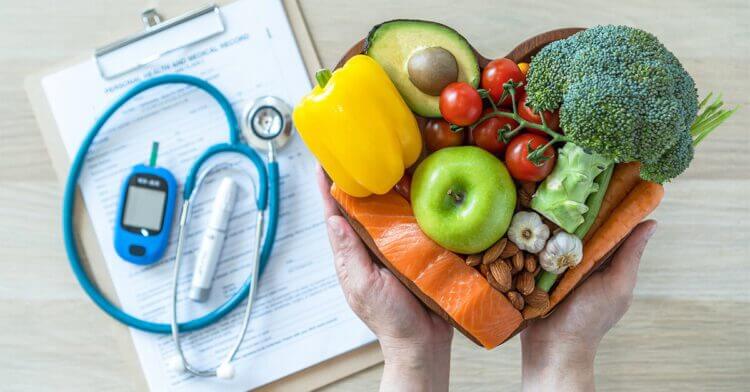 Stethoscope on clipboard with hands holding a bowl of veggies