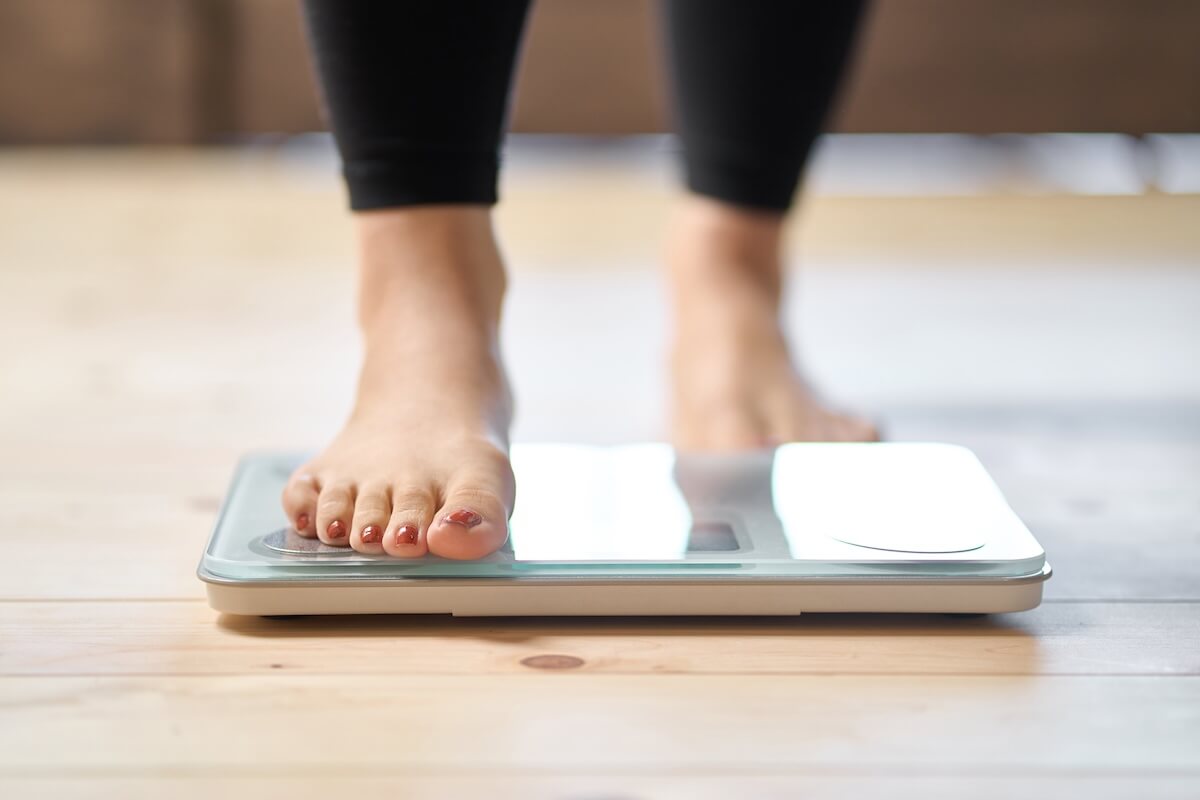 Close-up of a womans feet as she is stepping on to home digital scale to check weight.